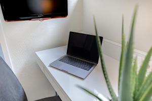 a laptop sitting on a white table with a tv at Select Hotel Berlin Checkpoint Charlie in Berlin