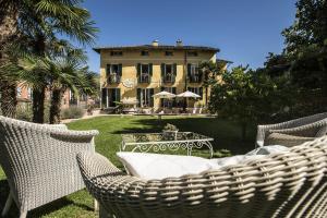 une maison avec des chaises en osier et une table dans la cour dans l'établissement Swiss Historic & Garten Hotel Villa Carona, à Carona