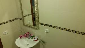 a bathroom with a sink with a mirror and flowers at Il Palazzetto dei Briganti in Guardiaregia