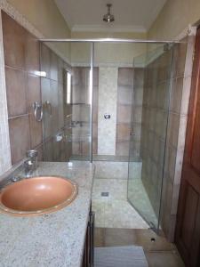 a bathroom with a glass shower and a sink at Ha'Penny Hill in Tzaneen