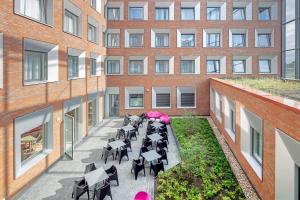 an internal courtyard of a building with tables and chairs at prizeotel Münster-City in Münster