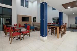 a dining room with tables and chairs and a tv at Holiday Inn Express Fresno South, an IHG Hotel in Fresno