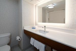 a bathroom with a toilet, sink and mirror at Holiday Inn Express Fresno South, an IHG Hotel in Fresno