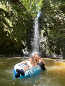 two women are riding on an raft in the water near a waterfall at ゲストハウス千倉のおへそ in Chikura