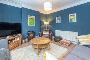 un salon avec une table et un mur bleu dans l'établissement Beautiful Redbrick Home in Ruthin Centre & Parking, à Ruthin