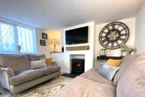 a living room with a couch and a clock on the wall at Cosy cottage 5 minutes walk to beach in Caister-on-Sea