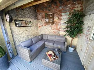 an outdoor patio with a couch and a table at Cosy cottage 5 minutes walk to beach in Caister-on-Sea