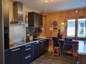 eine Küche mit schwarzen Schränken und einer Theke mit Stühlen in der Unterkunft A Cordon entre Bois et Nature in Cordon