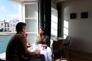 a man and woman sitting at a table in a restaurant at Hôtel Le Galion in Saint-Martin-de-Ré