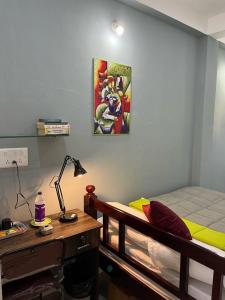 a bedroom with a bed and a desk with a lamp at Chez Prabha Homestay in Puducherry