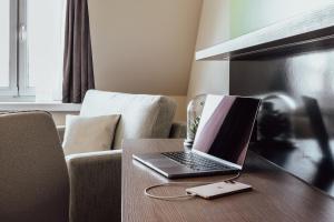 um computador portátil sentado numa mesa de madeira ao lado de um sofá em Select Hotel Style Berlin em Berlim