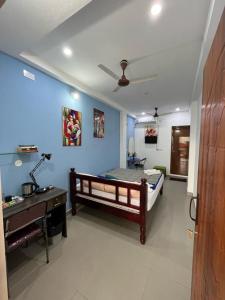 een slaapkamer met een bed en een bureau in een kamer bij Chez Prabha Homestay in Pondicherry