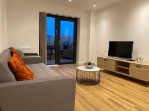 a living room with a couch and a flat screen tv at Triple t homes Cosy 2 bedroom Apartment with balcony in Ilford