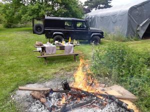 a picnic table and a fire in front of a tent at Office des bons enfants in Huy