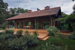 a house with a wooden deck in the yard at FERN dom mazurski in Mrągowo