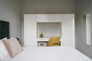 a bedroom with a white bed and a yellow chair at numa I Caja Apartments in Barcelona