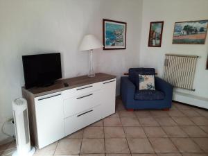 ein Wohnzimmer mit einem TV und einem Stuhl in der Unterkunft Appartamento sul lago Maggiore in Castelletto sopra Ticino
