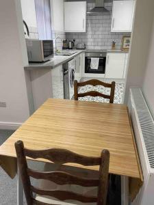 a kitchen with a wooden table and two chairs at Newly refurbished one bedroom apartment in Preston