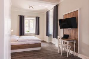 a bedroom with a bed and a desk and a tv at Die Sonne Nollingen in Nollingen