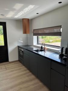 een keuken met zwarte werkbladen en een raam en een wastafel bij Bij De Kei Appelscha in Appelscha