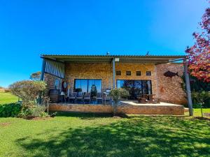 a brick house with a patio and chairs in a yard at Dullstroom Manor Game & Trout Lodge in Dullstroom