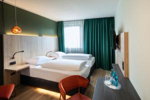 a hotel room with two beds and a table at ACHAT Hotel Monheim am Rhein in Monheim