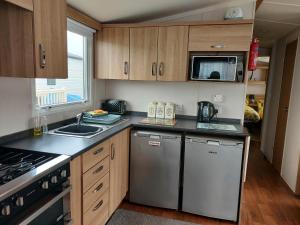 a kitchen with stainless steel appliances and wooden cabinets at 95 Holiday Resort Unity 3 bed passes included in Brean
