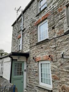 a stone building with a green door and windows at Cosycot in Gorran Haven