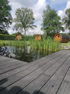 een veld met hooibalen in het gras naast een houten terras bij Gemütliches Schlaffass am Schwimmteich mit Heizung in Burg