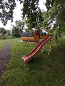 a playground with a slide in a park at Gemütliches Schlaffass am Schwimmteich mit Heizung in Burg