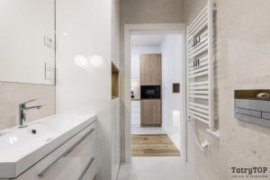 a white bathroom with a sink and a hallway at TatryTop Apartamenty Sabała in Zakopane +163 photos