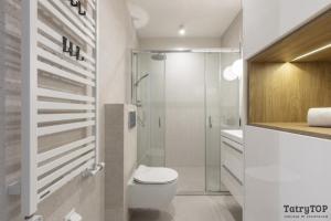 a white bathroom with a toilet and a shower at TatryTop Apartamenty Sabała in Zakopane