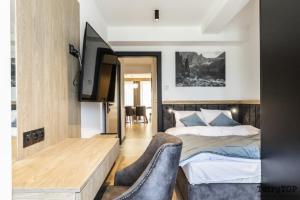 a bedroom with a bed and a desk and a tv at TatryTop Apartamenty Sabała in Zakopane