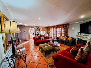 a living room with red couches and a fireplace at Dullstroom Manor Game & Trout Lodge in Dullstroom