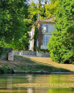 una casa en una colina junto a un cuerpo de agua en Vue de la Riviere, en Allemans