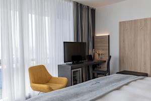 Habitación de hotel con cama, escritorio y TV. en Select Hotel Berlin Spiegelturm en Berlín