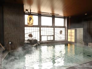 岡山市にある天然温泉　吉備の湯　ドーミーイン岡山の大きな窓付きの客室内の大きなスイミングプールを提供しています。