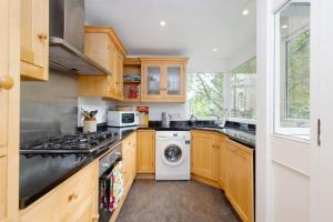 uma cozinha com armários de madeira e uma máquina de lavar e secar roupa em ALTIDO 3-bed Meadows flat near Castle em Edimburgo