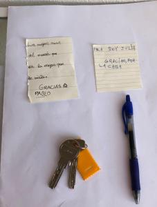 una mesa con llaves, una nota y un bolígrafo en INSULA PLAzA MAYOR ATICO, en Astorga