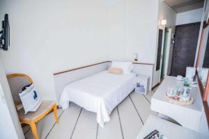Un pequeño dormitorio con una cama blanca y una silla en Hotel Gambrinus - Valentini Family Village, en Bellaria-Igea Marina