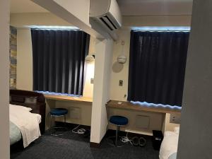 a room with two beds and a desk with two stools at Guest House M104 Kagoshima in Kagoshima