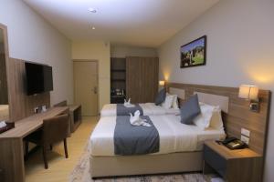 a hotel room with two beds and a desk at Triple E Hotel and Spa in Addis Ababa
