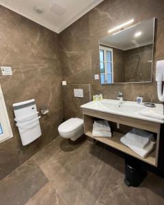 La salle de bains est pourvue d'un lavabo, de toilettes et d'un miroir. dans l'établissement Hôtel Le Galion, à Saint-Martin-de-Ré