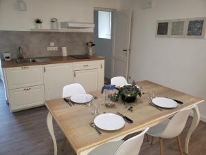 una mesa de madera con platos blancos y sillas en la cocina en Appartement FONTARRABIE, en Saint-Jacques