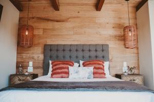 a bedroom with wooden walls and a bed with red pillows at De Uijlenes in Gansbaai