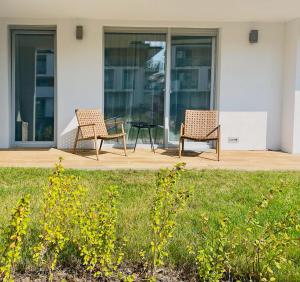 two chairs and a table in front of a building at Apartament Family Premium - Baltic Sun Sztutowo in Sztutowo