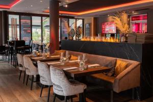 a restaurant with wooden tables and chairs and a bar at Qube Hotel Bergheim in Heidelberg