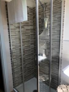 a shower with a glass door in a bathroom at Cielo Apartment in Forlì