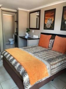 a bedroom with a large bed with an orange blanket at Klein Kavali Studio's in Eikenhof