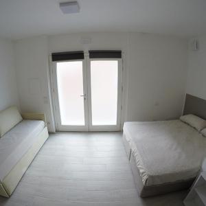 Dieses weiße Zimmer verfügt über 2 Betten und ein großes Fenster. in der Unterkunft Corso95 SrL in Iesi